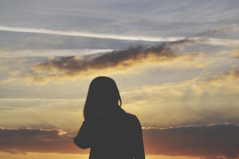 Silhouette of a woman at sunset, symbolizing healing, reflection, and emotional growth for therapy clients in Upland, CA.