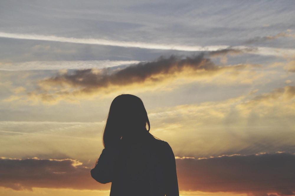 Silhouette of a woman at sunset, symbolizing healing, reflection, and emotional growth for therapy clients in Upland, CA.