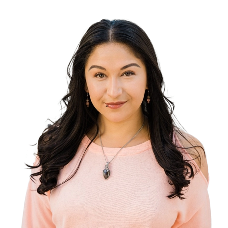 Woman with long dark hair wearing a light pink top and a pendant necklace, looking directly at the camera against a transparent background.